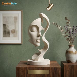 May include: A cream-colored sculpture of a woman's face with closed eyes and flowing lines. The sculpture is on a round base and sits on a dark wood surface. A vase with dried flowers is to the right.