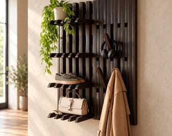 May include: A dark brown wooden wall-mounted organizer featuring vertical slats, horizontal shelves, and hooks. The unit holds a potted green plant, a pair of gray sneakers, a beige handbag, black headphones, and a tan trench coat.