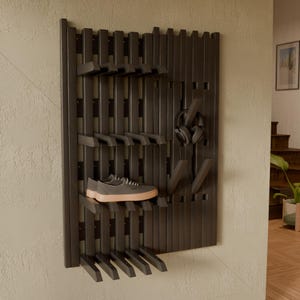 May include: A dark brown wall-mounted organizer rack featuring vertical slats and adjustable horizontal pegs. The rack holds a pair of gray sneakers with light-colored soles on one shelf and a pair of black over-ear headphones on a hook.