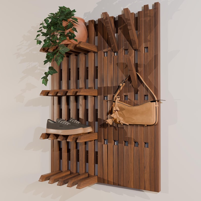 May include: A wooden wall-mounted shelf unit with multiple shelves and hooks. It displays a terracotta pot with a green plant, a pair of green sneakers, and a tan handbag. The unit is made of dark brown wood.