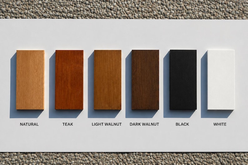 May include: A rectangular display board featuring six vertical wood color samples arranged in a row. The labels below each sample are Natural, Teak, Light Walnut, Dark Walnut, Black, and White, showing a range of wood tones and finishes.