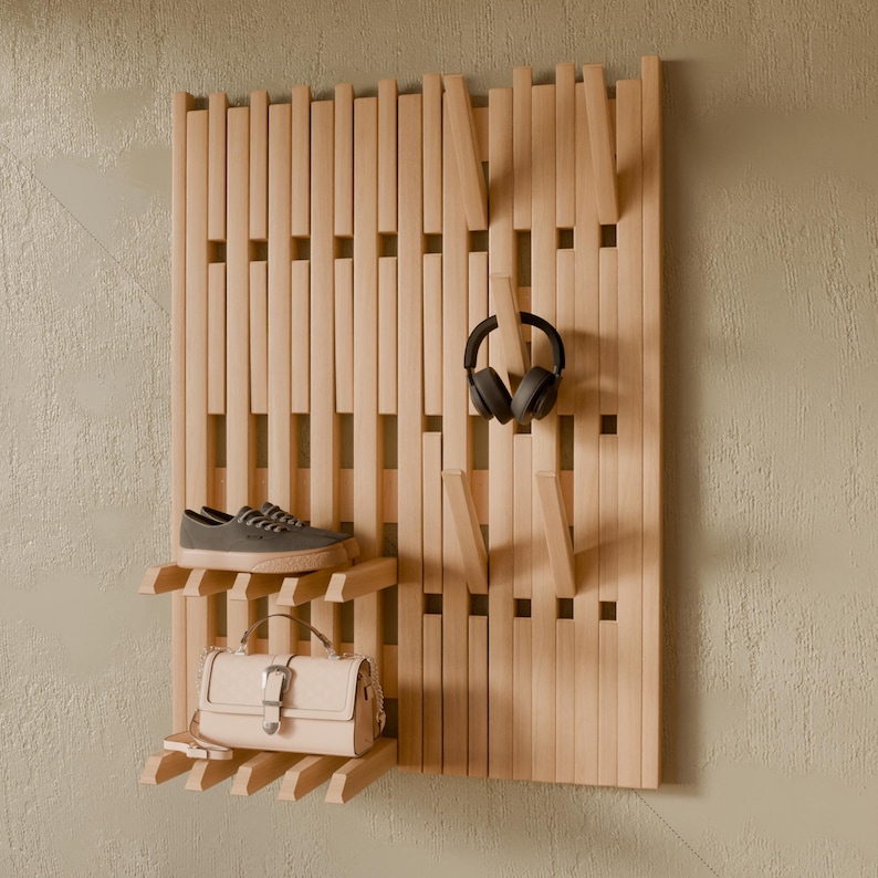 May include: A light-colored wooden wall-mounted organizer featuring vertical slats, integrated shelves, and protruding hooks. A pair of gray sneakers sits on the top shelf, a beige handbag rests on the bottom shelf, and black headphones hang from a hook.