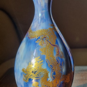 May include: A blue and gold decorative vase with a dragon design. The vase has a slender neck and a rounded body. The dragon is depicted in gold against a blue background.