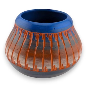 May include: A small, rounded ceramic pot featuring a vibrant blue rim and a dark base. The body displays a horizontal gradient of brown and grey tones, overlaid with vertical, textured orange lines that create a distinct, raised pattern.