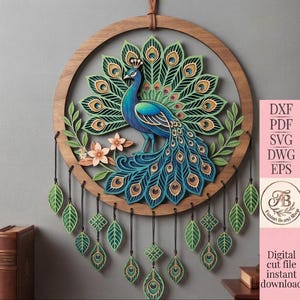 Peut inclure: Une décoration murale circulaire en bois présentant un motif de paon superposé dans des tons de bleu, vert et or. Le paon est entouré de feuilles et de fleurs, avec des breloques en forme de feuilles et de motifs géométriques suspendues.