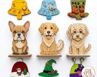 May include: A collection of nine decorative wooden cutouts featuring three hats, three dogs, a Santa hat, a witch hat, and a monster. The hats include yellow, blue, and green designs. The dogs are a French Bulldog, a Golden Retriever, and a Doodle.