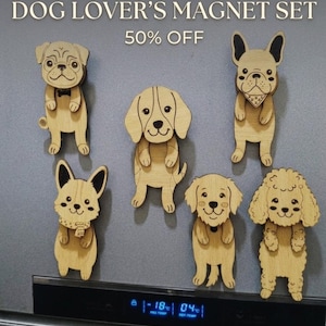 May include: A set of six wooden dog magnets in various breeds, including a pug, French bulldog, and poodle. Each magnet is light brown with black detailing and features a smiling dog face. The text "DOG LOVER'S MAGNET SET" is at the top.