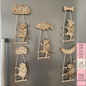Peut inclure: Un ensemble de six décorations murales en bois découpé au laser représentant des animaux et des aliments, dont une vache, un chat, un chien, un hamster, un singe, du fromage, un poisson et une banane, suspendus à une échelle de corde.