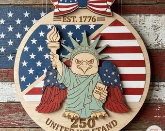 May include: Wooden patriotic wall hanging featuring a stylized Statue of Liberty with an eagle's head, holding a torch and a sign that reads "USA 250." The design incorporates the American flag, the text "EST. 1776," and "UNITED WE STAND."