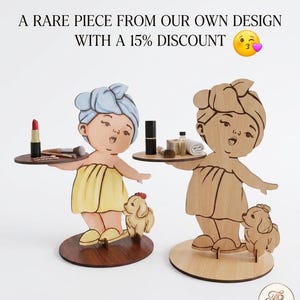 Puede incluir: Dos figuras decorativas de madera de niñas sosteniendo bandejas, una pintada con color y la otra en madera natural. Cada figura tiene un perro pequeño a sus pies. El texto dice "Una pieza rara de nuestro propio diseño".