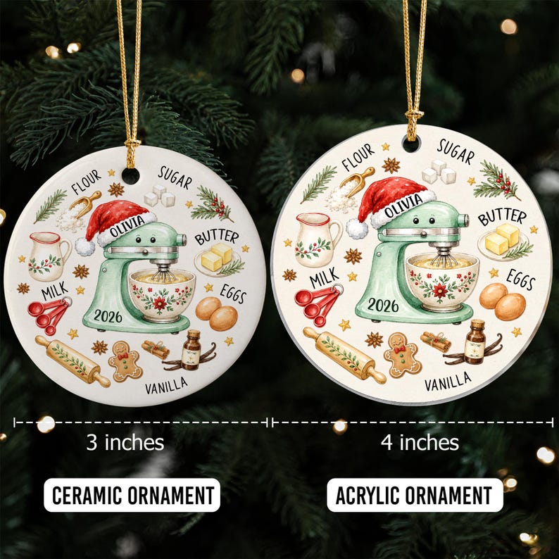 May include: Two round ornaments featuring a light green stand mixer with a Santa hat, the name Olivia, and the year 2026. Illustrations include flour, sugar, butter, eggs, milk, vanilla, and a gingerbread man. One is a 3-inch ceramic ornament, the other a 4-inch acrylic ornament.