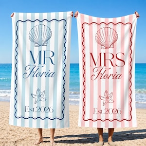May include: Two beach towels, one blue and white striped with "MR Floria" and a seashell and starfish graphic, the other pink and white striped with "MRS Floria" and similar graphics. Both say "Est.2026".