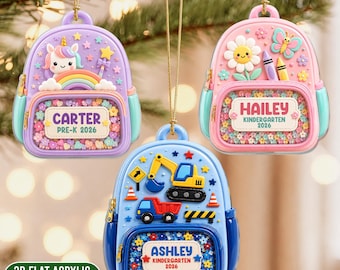 Könnte beinhalten: Drei rucksackförmige Ornamente, die an goldenen Schnüren hängen. Das lila Modell zeigt ein Einhorn, einen Regenbogen und den Text CARTER PRE-K 2026. Das rosa Modell hat eine Blume, einen Schmetterling und HAILEY KINDERGARTEN 2026. Das blaue Modell zeigt Baufahrzeuge und ASHLEY KINDERGARTEN 2026.
