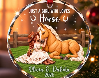 Könnte beinhalten: Ein rundes, klares Glasornament mit einer gedruckten Illustration einer Person mit Cowboyhut und weißem Kleid, die neben einem hellbraunen Pferd auf grünem Gras sitzt. Der Text lautet: JUST A GIRL WHO LOVES Horse, Olivia & Dakota, 2026.