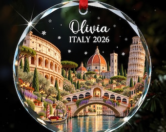 Könnte beinhalten: Ein rundes, facettiertes Glasornament mit rotem Bandaufhänger, das eine gedruckte Collage italienischer Wahrzeichen wie das Kolosseum, den Dom von Florenz und den Schiefen Turm von Pisa zeigt, mit dem Text Olivia und ITALY 2026.