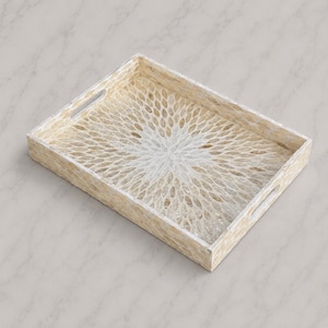 May include: A rectangular serving tray featuring a decorative inlay of iridescent shell pieces arranged in a radiating sunburst pattern. The tray has a light beige and white color palette with integrated cutout handles on two opposing sides.
