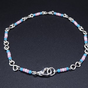 May include: A silver chain bracelet with blue, pink, and white beads. The bracelet has a lobster clasp closure.