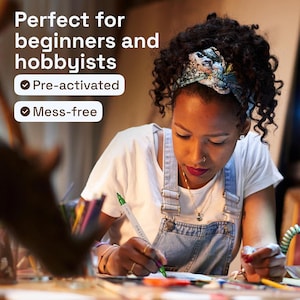 K&ouml;nnte beinhalten: Eine Person in einem wei&szlig;en T-Shirt und einer Jeans-Latzhose zeichnet mit einem gr&uuml;nen Marker. Das Bild enth&auml;lt den Text "Perfect for beginners and hobbyists", "Pre-activated" und "Mess-free".