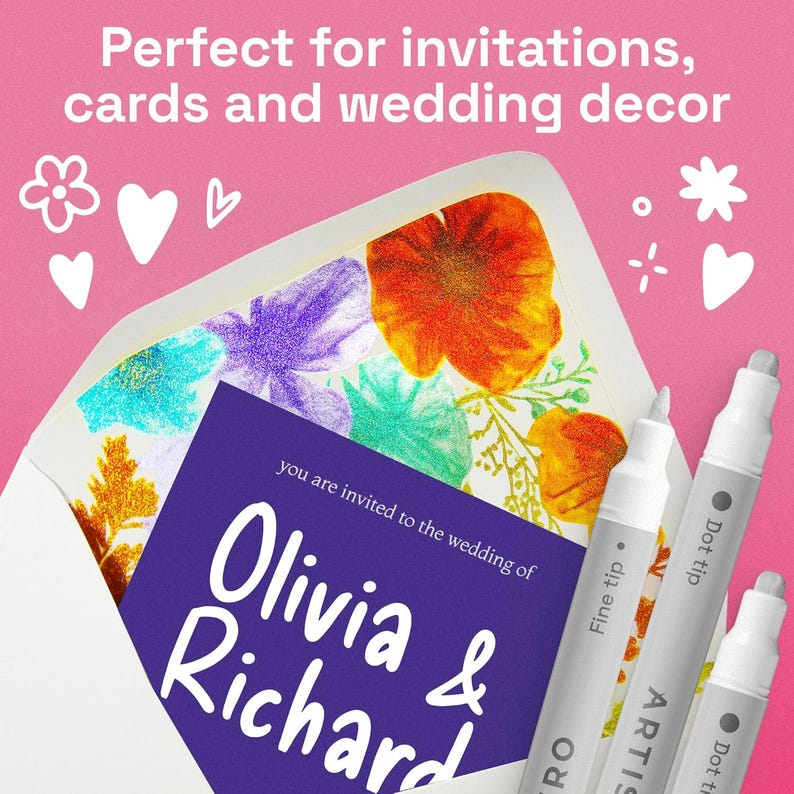 May include: A wedding invitation with floral artwork is partially visible inside a white envelope. The invitation card is purple with white text that reads "Olivia & Richard". Three silver and white ARTIS pens are in the foreground.
