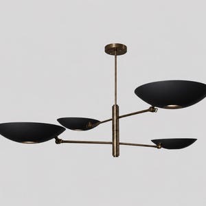 May include: A modern chandelier with four black, bowl-shaped shades. The shades are suspended from a central brass-colored stem and arms. The light fixture is designed for ceiling mounting and provides ambient lighting.