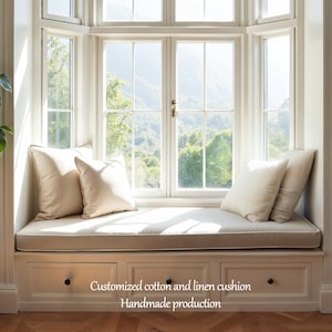 May include: A window seat with a cream-colored cushion and matching pillows. The seat is built into a white cabinet with drawers. The text on the cabinet reads "Customized cotton and linen cushion Handmade production."