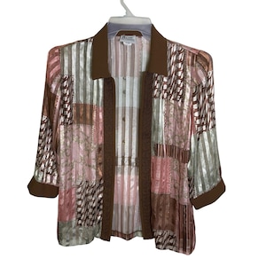 May include: A patchwork-style jacket with a brown collar and trim. The jacket features a mix of pink, brown, and silver fabrics in various patterns. The sleeves are three-quarter length. The jacket is hanging on a white hanger.