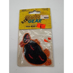 May include: An armadillo-shaped seed bead applique in black, orange, and red, packaged on a yellow Western Gear card labeled RHW464 ARMADILLO, 2 inches by 3.5 inches, 1 piece per package, with visible handwritten and orange sale price stickers.