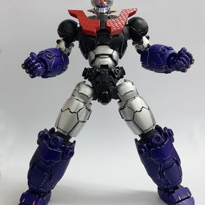 May include: A robotic action figure featuring a black, silver, and purple color scheme. The figure has a red chest plate with a honeycomb pattern, a silver head with blue and red accents, and articulated limbs with clenched fists in a standing pose.
