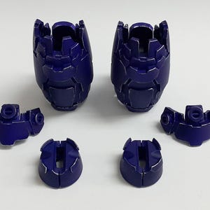 May include: A set of six dark purple plastic model kit components, including two large segmented leg armor pieces, two smaller shoulder or hip armor sections with circular connectors, and two small circular base or joint covers.