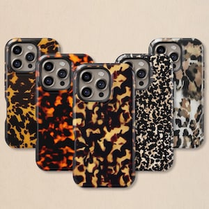 Può includere: Cinque custodie per telefono con vari design animalier. Le custodie presentano una finitura lucida e un design protettivo. I motivi includono tartaruga, leopardo e stampe astratte nei toni del marrone, nero e beige.