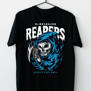 May include: Black t-shirt featuring a grim reaper graphic in white and blue. The design includes the word "REAPERS" in a dripping font, a skull, and the text "HAUNTED SINCE MMXII". The shirt is hanging on a black hanger.