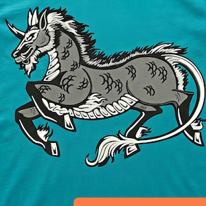 Könnte beinhalten: Türkisfarbenes T-Shirt mit einer stilisierten Illustration eines Fabelwesens mit Horn, grauem Körper und schwarzen Akzenten. Der Text "Embroidery by Husain" und "instant download and custom available" sind auf dem Shirt zu sehen.