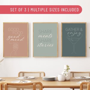 Puede incluir: Juego de tres impresiones artísticas enmarcadas con citas inspiradoras. Las impresiones presentan las frases "Good Food good mood", "Share meals Share stories" y "Gather & enjoy". Cada impresión tiene un fondo de color diferente y un diseño minimalista.