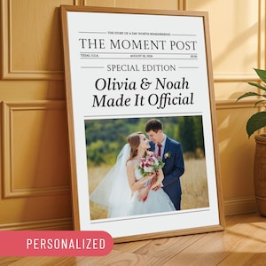 Puede incluir: Una impresión enmarcada diseñada para parecerse a una portada de periódico. El titular dice "The Moment Post" con el texto "Olivia & Noah Made It Official" y una foto de una pareja. La palabra "PERSONALIZADO" está en la parte inferior.