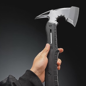 Könnte beinhalten: Eine taktische Tomahawk-Axt mit silberfarbenem Kopf und schwarzem Griff. Die Axt hat eine scharfe Klinge, einen Hammerkopf und einen strukturierten Griff. Das Design ist robust und funktional.