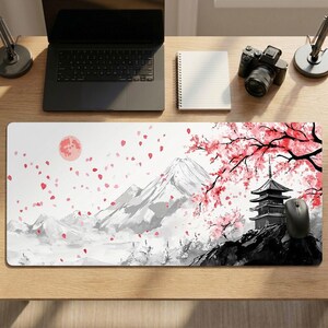 Op de afbeelding: Witte rechthoekige bureaumat met een Japans geïnspireerd ontwerp. Het kunstwerk bevat een bergketen, een pagode en kersenbloesems in rood en roze. Een volle maan is ook zichtbaar.