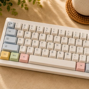 May include: A white mechanical keyboard with off-white keycaps. The keyboard has a compact layout with colorful accent keys, including yellow, green, and pink. The keys are labeled with standard characters and symbols.