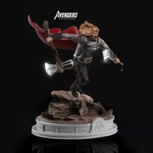 Może przedstawiać: Szczegółowa figurka Thora z Avengers: Endgame. Postać jest dynamicznie ustawiona, z czerwonym płaszczem powiewającym za nim. Trzyma świecący młot i topór. Podstawa jest biała z celtyckim wzorem węzła. Wysokość około 25 cm.