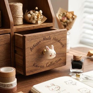 Może przedstawiać: Drewniany organizer na biurko z szufladą z uroczym uchwytem w kształcie królika. Szuflada jest oznaczona napisem "Artisan-Made Hardware" i "Kawaii Collection". Organizer ma również półki.