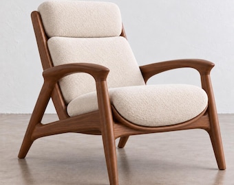 May include: An armchair featuring a dark brown wooden frame with curved armrests and legs. The seat, backrest, and headrest are upholstered in a textured, off-white cream fabric. The design includes a separate headrest cushion.