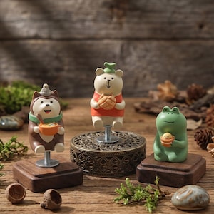 May include: Three whimsical figurines: a brown husky, a white bear, and a green frog. Each holds a small bowl or bread. The husky and frog sit on wooden blocks, while the bear is mounted on a decorative metal base. The background is a wooden surface.