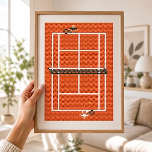Peut inclure: Broderie au point de croix encadrée représentant un court de tennis. Le court est orange avec des lignes blanches, un filet noir et vert, et une balle de tennis jaune. L'œuvre est présentée dans un cadre en bois.