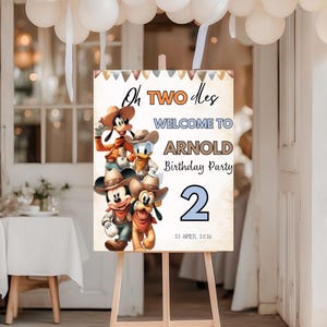 May include: A wooden easel displaying a birthday party welcome sign. The sign features Mickey Mouse, Goofy, Donald Duck, and Pluto in cowboy attire. Text includes "Oh Two Dles", "Welcome to Arnold Birthday Party", the number "2", and the date "27 April 2026".