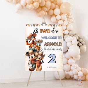 May include: A party welcome sign on an easel with the text "Oh Two Dles Welcome to Arnold Birthday Party 2 27 April 2026". The sign features cartoon characters Mickey Mouse, Goofy, Donald Duck, and Pluto.