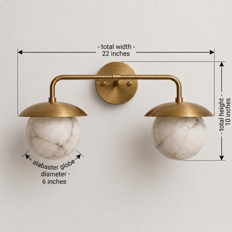 May include: A brass wall light fixture with two white alabaster globes. The fixture has a total width of 22 inches, a total height of 10 inches, and each alabaster globe has a diameter of 6 inches. The design features a central circular mount.