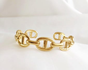 Adjustable gold-tone stainless steel marine link bangle bracelet with anchor link design.