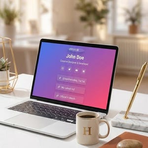 以下が含まれることがあります： John Doe, Creative Designer & DeveloperのプロフィールとSNSリンクが表示されたノートパソコン。そばにはHと書かれたクリーム色のマグカップ、石が置かれた茶色のノート、大理石の台座に乗った金色のペン、H Studioと書かれた小さな箱があります。
