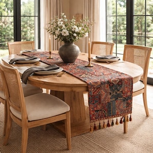 May include: A wooden dining table set for a meal. The table has a patterned runner, plates, and silverware. Wicker-backed chairs surround the table. A vase of flowers and candles complete the setting. The table is approximately 152 cm in diameter.