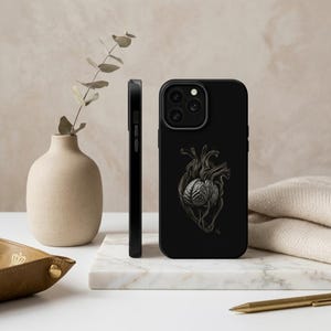 Peut inclure: Coque de téléphone noire avec une illustration détaillée d'une fusion cœur-cerveau. Le design est en nuances de gris et de noir, sur fond noir uni. L'étui est présenté sous plusieurs angles, soulignant son design élégant et ses caractéristiques de protection.