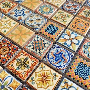 May include: Close-up of a mosaic tile sheet with many small, square tiles. Each tile displays detailed patterns in blue, yellow, orange, and green. The designs include floral motifs, geometric shapes, and stylized patterns, creating a vibrant and decorative surface.